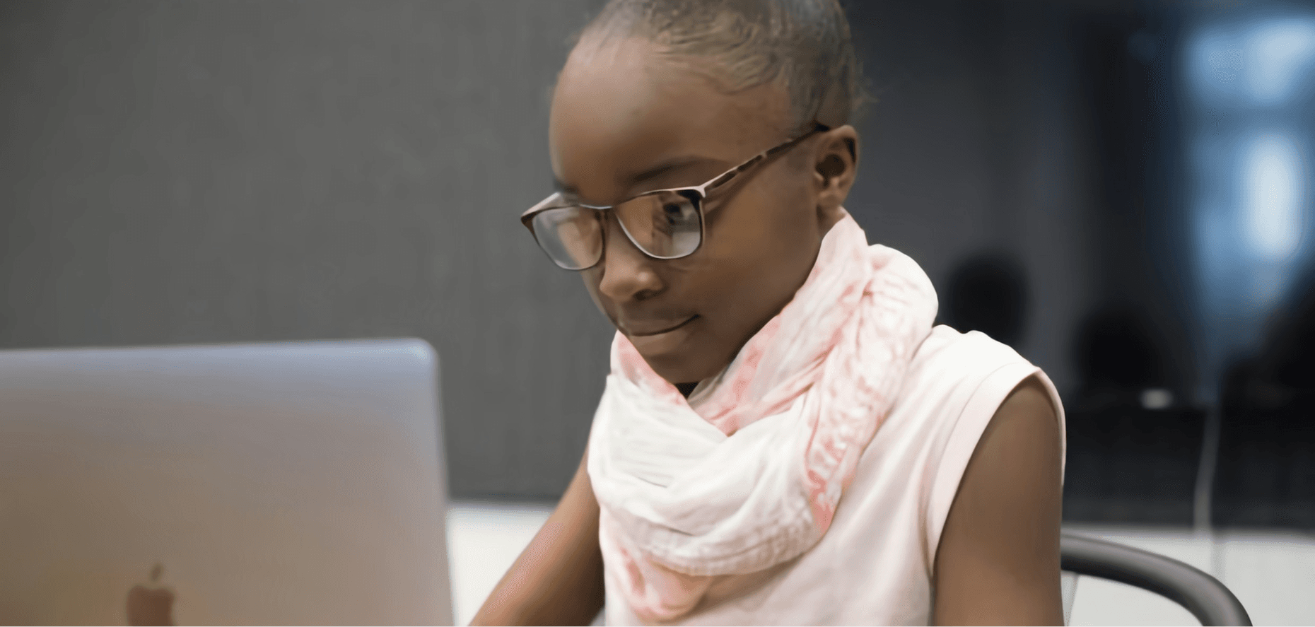 A young girl in glasses concentrating on her laptop during a study session